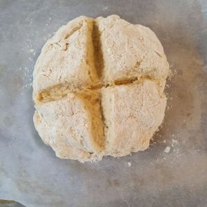 Image of an uncooked soda bread loaf with a cross cut in